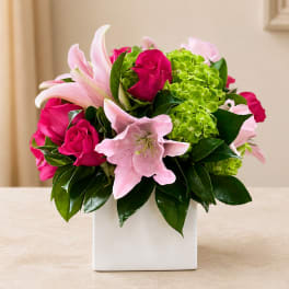 Pink lilies and hot pink roses in a white square vase