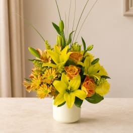 Yellow lilies and orange roses arranged in a white vase