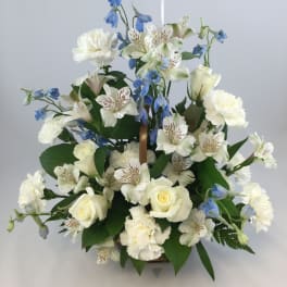 White roses, alstroemeria, and blue flowers in a basket arrangement