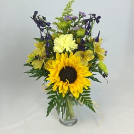 Sunflower bouquet with purple and yellow flowers in a glass vase