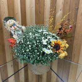 Fall floral arrangement in a woven basket with a scarecrow decoration