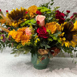 Mixed bouquet with sunflowers, roses, and mums in a green vase