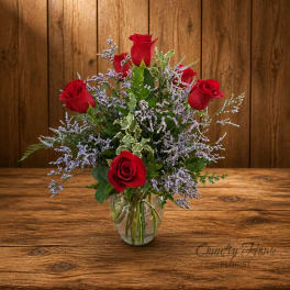 Red roses in a clear glass vase with lavender filler flowers