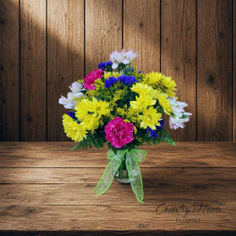 Colorful mixed bouquet in a clear vase with a green ribbon