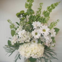 White daisies and hydrangea in a glass vase with green accents