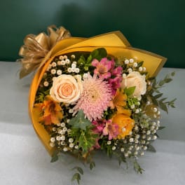 Bouquet of peach and pink flowers wrapped in gold paper