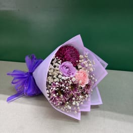 Bouquet of purple, pink, and white flowers wrapped in lavender paper