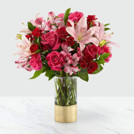 Pink and red mixed bouquet in a clear glass vase with a gold base