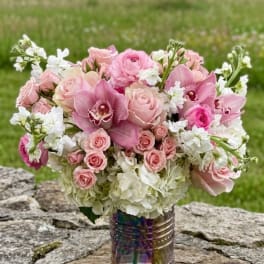 Pink roses and orchids arranged in a vase with white flowers