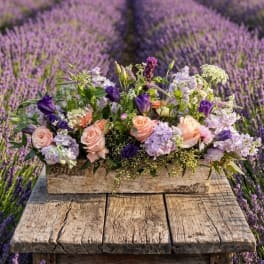Pastel floral arrangement in a rustic wooden box on a weathered table