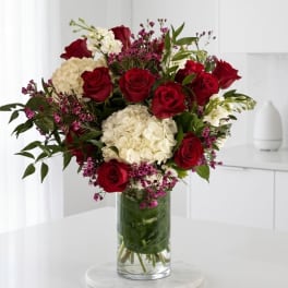 Red roses and white hydrangeas in a clear glass vase