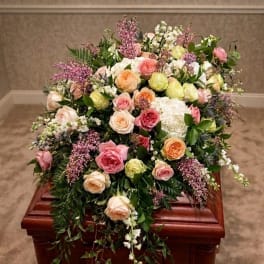 Pastel rose arrangement on a wooden casket