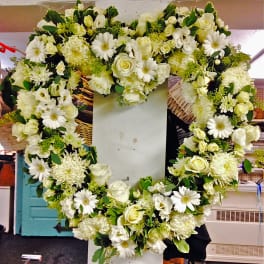 Heart-shaped white floral wreath on a stand