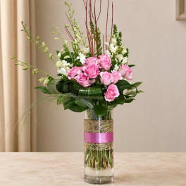 Pink roses and white snapdragons in a tall glass vase with a pink ribbon