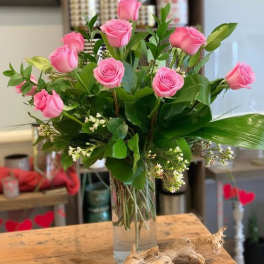 Pink roses arranged in a clear glass vase with greenery