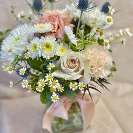 Mixed bouquet with cream roses, peach carnations, and small white daisies in a glass vase