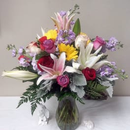 Mixed bouquet of roses, lilies, and daisies in a glass vase