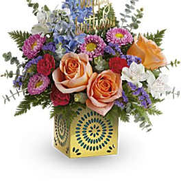 Colorful birthday flower arrangement with peach roses in a yellow cube vase and happy birthday pick