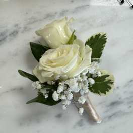 White rose boutonniere with baby's breath and variegated leaves