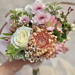 Handheld bouquet of pink and peach flowers with a white rose