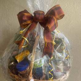 Gift basket of assorted packaged foods wrapped in cellophane with a plaid bow