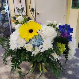 Mixed bouquet with yellow gerbera, white roses, and blue flowers in a vase
