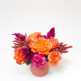 Orange and pink flower arrangement in a pink vase
