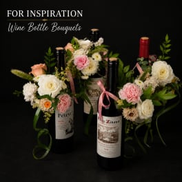 Wine bottles decorated with small floral bouquets and ribbons