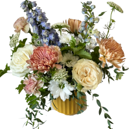 Mixed bouquet of roses, chrysanthemums, and blue delphinium in a yellow vase