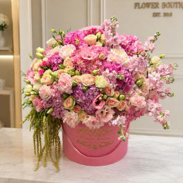 Large pink flower arrangement in a round pink box