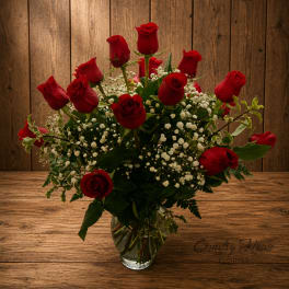 Red roses arranged in a clear glass vase with white filler flowers