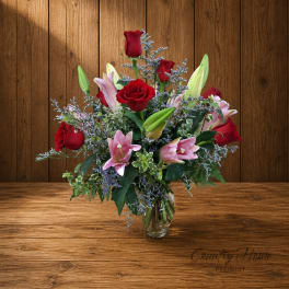 Red roses and pink lilies arranged in a clear glass vase