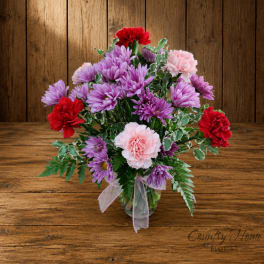 Bouquet of purple chrysanthemums and pink carnations in a glass vase
