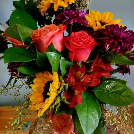 Bouquet of sunflowers, roses, and red alstroemeria with an orange ribbon