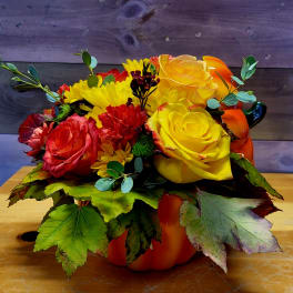 Bouquet of yellow and red roses with daisies in a pumpkin container