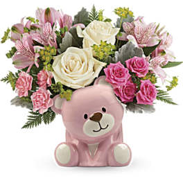 Pink teddy bear vase holding roses and pink flowers