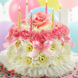 Pink and white floral cake with lit striped candles