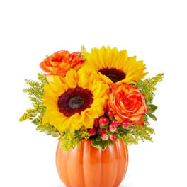 Sunflowers and orange roses in an orange pumpkin vase