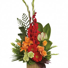 Tropical arrangement with red, orange, and green flowers in a wooden container