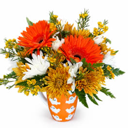 Orange and yellow mixed flower bouquet in a Halloween mug