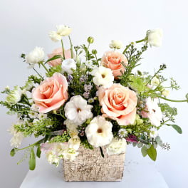 Peach and white rose arrangement in a textured square container