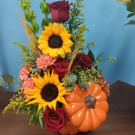 Autumn bouquet with sunflowers, red roses, and a pumpkin container