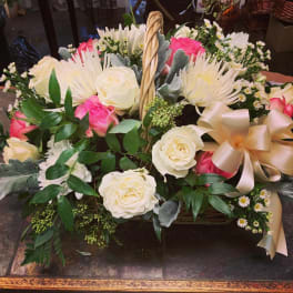 Basket arrangement of white and pink roses with a large satin bow