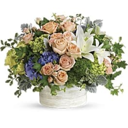 Peach roses and white lilies in a white round container