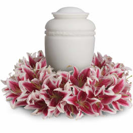 White cremation urn encircled by a ring of pink and white lilies