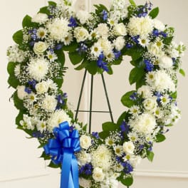 Heart-shaped floral wreath with white and blue flowers on a stand