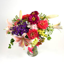 Colorful bouquet of zinnias and lilies in a glass vase