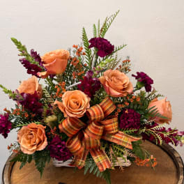 Peach roses and deep purple carnations in a white basket with a plaid bow