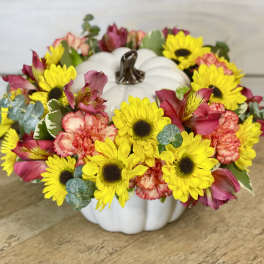 Sunflower and pink flower arrangement in a white pumpkin container