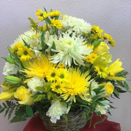 Yellow and white mixed flower arrangement in a wicker basket